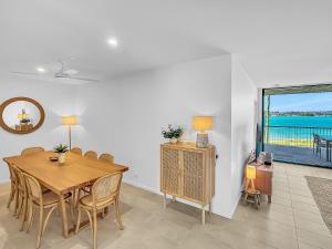 Un comedor con mesa y vista al mar. en 3-Bed: Riverfront Alfresco Dining & Rooftop Pool, en Batemans Bay