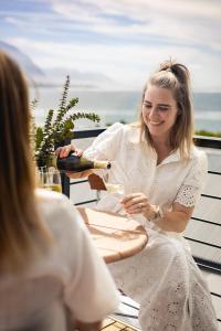 赫曼努斯Oceanfront Studios - Hermanus Waterfront Apartments的坐在桌子旁的女人,喝一杯酒