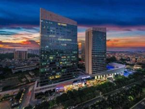 a city skyline with a tall building at night at Mandolin Intelligent Hotel Jinagmen in Jiangmen