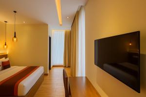 um quarto de hotel com uma cama e uma grande televisão de ecrã plano em The Miste Munnar By D2V em Munnar