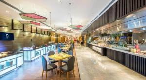 une salle à manger avec des tables et des chaises dans un restaurant dans l'établissement The QUBE Hotel Jingzhou, à Caoshi