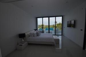 une chambre blanche avec un lit et une grande fenêtre dans l'établissement Sansuri Resort, à Surin Beach 181 autres photos