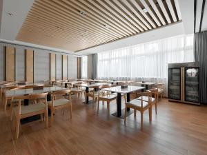 une salle à manger avec tables, chaises et fenêtres dans l'établissement GreenTree Inn Wuhu Eshan Road University City, à Wuhu