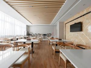 un restaurant avec des tables et des chaises ainsi qu'une télévision murale. dans l'établissement GreenTree Inn Wuhu Eshan Road University City, à Wuhu