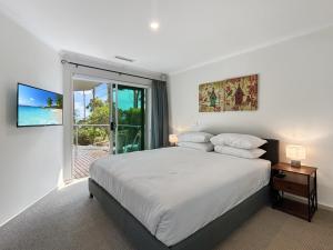 Un dormitorio blanco con una cama y una ventana grande. en Spacious 4-Bed Home with Coastal Charm, en Long Beach