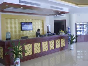 a woman sitting at a counter in a lobby at GreenTree Inn Heze Railway Station Hotel in Zhaolou