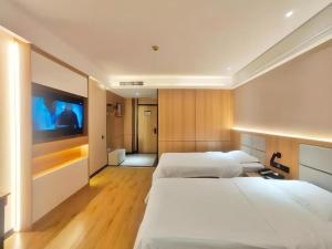 a hotel room with two beds and a flat screen tv at GreenTree Inn Heze Railway Station Hotel in Zhaolou +177 photos