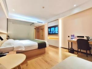 a hotel room with a bed and a desk and a tv at GreenTree Inn Heze Railway Station Hotel in Zhaolou +158 photos