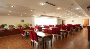 un restaurant avec des chaises et des tables rouges dans une salle dans l'établissement GreenTree Inn Tianjin Wuqing Distric Bohai Market, à Dadunqiu