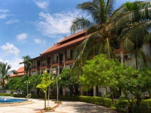 a building with a palm tree and a swimming pool at Xishuangbanna Hotel Managed by Xandria Hotel in Ban Nongkham