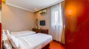 um quarto de hotel com duas camas e uma janela em GreenTree Inn Shanghai South Railway Station Xujiahui Stadium Subway Station Shell Hotel em Xangai