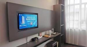 a living room with a flat screen tv on a wall at GreenTree Inn HanZhong Railway Station Beiyihuan Road Express Hotel in Shima