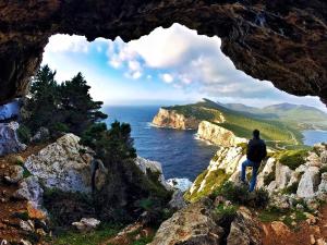 un hombre sentado en un acantilado mirando al océano en Il Pozzo Dei Desideri en Arbus