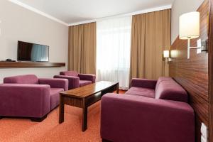 a hotel room with purple couches and a tv at Hotel Euro in Pardubice