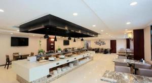 ein Restaurant mit Theke und Tischen und Stühlen in der Unterkunft GreenTree Inn Jiangsu Suzhou New District Science and Technology College Business Hotel in Suzhou