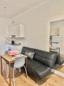 Una sala de estar con un sofá de cuero negro y una mesa. en Standard Whitmore Guesthouse, en Adelaida