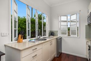 une cuisine avec un évier et deux fenêtres dans l'établissement Charming 1-Bed Cottage with Garden Retreat, à Bald Hills 17 autres photos