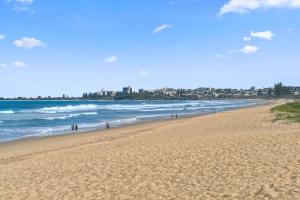 a group of people walking on the beach at Palm Cove Retreat - Walk to beach & CBD in Maroochydore