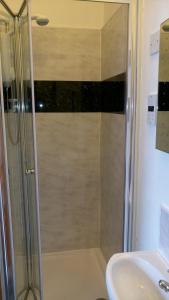 a shower with a glass door next to a sink at Knight's Rest Guest House in Airdrie
