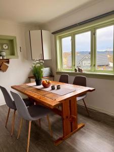 una cucina con tavolo in legno, sedie e finestre di Haus Harald a Tysnes