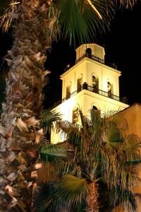 a white lighthouse with a palm tree in front of it at Hotel Mission De Oro in Santa Nella Village