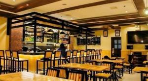 un restaurant avec des tables et des chaises en bois et un bar dans l'établissement Cebu Northwinds Hotel, à Cebu