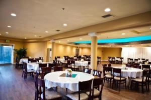 ein Esszimmer mit weißen Tischen und Stühlen in der Unterkunft Hotel Saddleback in Norwalk