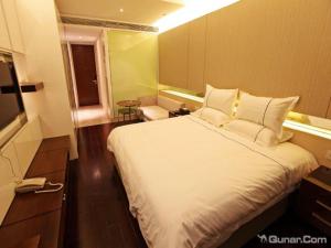 une chambre avec un grand lit blanc et une télévision dans l'établissement Nanjing YuTimes Hotel, à Nankin