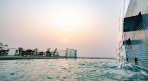 a pool of water with the sun setting behind a building at Hotel Castle Salam in Khulna