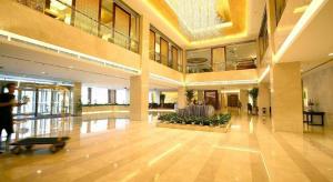 un grand hall d'entrée avec une personne marchant dans un bâtiment dans l'établissement Qingdao Blue Horizon Hotel Licang, à Laoshan