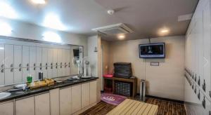ein Badezimmer mit Waschbecken und einem Fernseher an der Wand in der Unterkunft CJ Tourist Hotel in Jeju-do