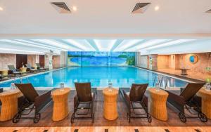 une grande piscine avec des chaises dans un hôtel dans l'établissement New Century Shaoxing Grand Hotel, à Shaoxing