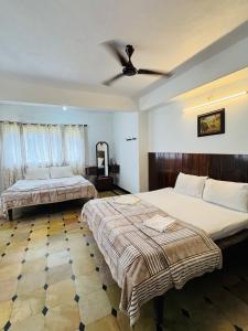 a bedroom with two beds and a ceiling fan at Hotel caveri comfort in Madikeri