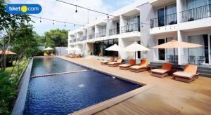 une piscine avec chaises et parasols à côté d'un bâtiment dans l'établissement Double G Resort Anyer, à Babagan