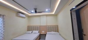 two beds in a room with a ceiling at Sri Srinivasa Lodge in Mārkāpur