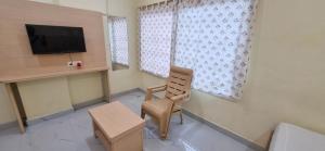 a room with a chair and a tv and windows at Sri Srinivasa Lodge in Mārkāpur