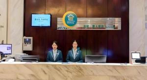 deux personnes assises à un comptoir dans une pièce dans l'établissement City Comfort Inn Guigang Tangren Street, à Guigang