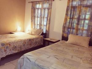 ein Schlafzimmer mit zwei Betten und einem Fenster mit Vorhängen in der Unterkunft Bosque de Ángeles in Buena Vista