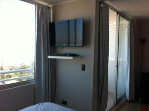 1 dormitorio con TV en la pared junto a una ventana en Barcelo Suites Viña del Mar, en Viña del Mar