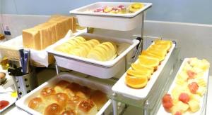 a shelf with several trays of bread and other pastries at City Comfort Inn Jingmen Zhongxiang Chengtian Huafu in Zhongxiang