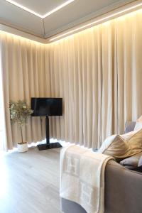 a living room with curtains and a couch and a television at Galactic getaways JUPITER in Prestatyn