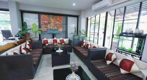 ein Wohnzimmer mit Sofas, Tischen und Fenstern in der Unterkunft Sripoom Boutique House in Chiang Mai