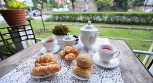 ein Tisch mit Tassen Tee und Gebäck darauf in der Unterkunft Sripoom Boutique House in Chiang Mai