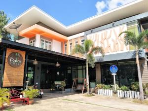 ein Gebäude mit Palmen davor in der Unterkunft The Palm Village in Ban Non Chan