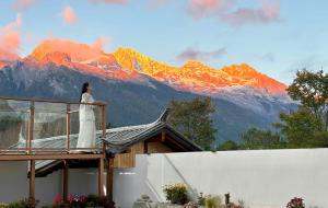 a woman standing on top of a house with a mountain at Lijiang Hengchang Baoyin Mohuakai Inn in Lijiang