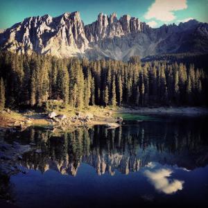 a mountain reflection in a lake in front of trees at Casa al Lago di Carezza - Dolomiti in Carezza al Lago