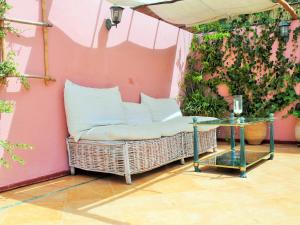 um sofá de vime contra uma parede rosa com uma mesa de vidro em Christina's House em Asilah