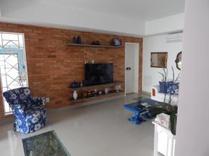 a living room with a tv on a brick wall at Vila Hibisco Pousada e Apart in Vassouras