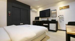 a bedroom with a white bed and a black door at Hotel Look in Daejeon