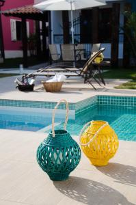 three vases sitting next to a swimming pool at Vila Hibisco Pousada e Apart in Vassouras